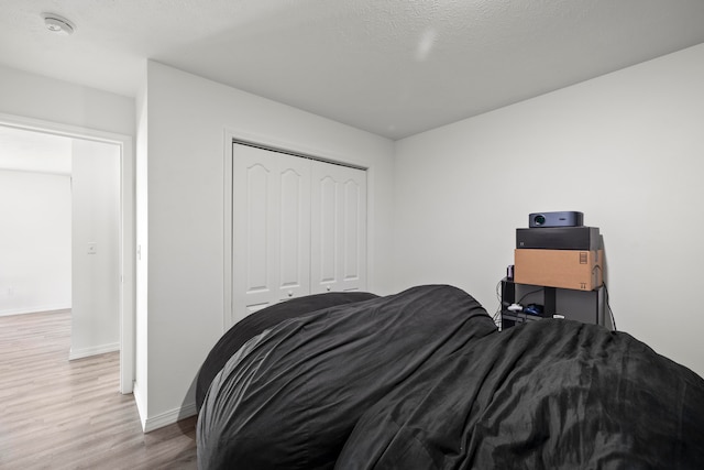 bedroom featuring a closet, light hardwood / wood-style flooring, and a textured ceiling