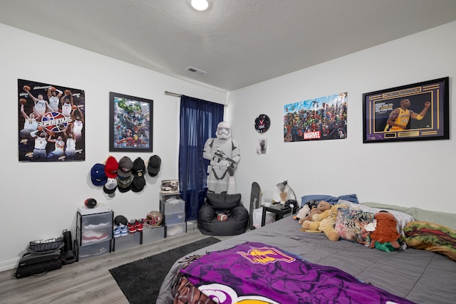 bedroom featuring hardwood / wood-style flooring and a textured ceiling