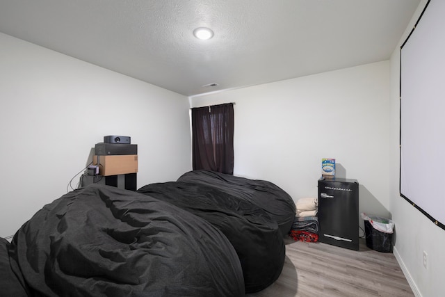 bedroom with light hardwood / wood-style floors and a textured ceiling