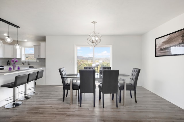 dining space featuring dark wood-type flooring, sink, and a chandelier