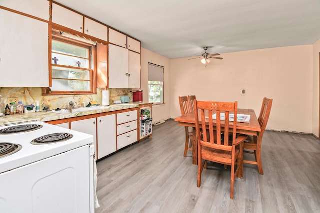 kitchen featuring plenty of natural light, white electric range, light hardwood / wood-style flooring, and white cabinetry