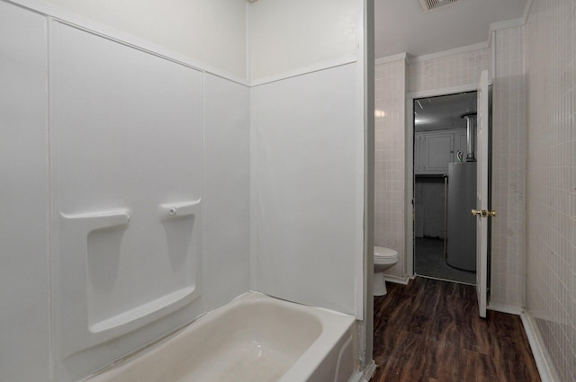 bathroom with washtub / shower combination, hardwood / wood-style flooring, and toilet