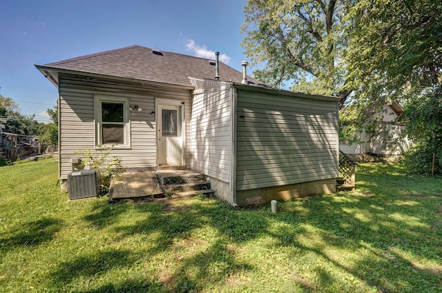 back of property with central AC unit and a lawn