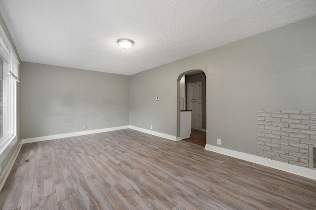 empty room featuring a textured ceiling and light hardwood / wood-style flooring