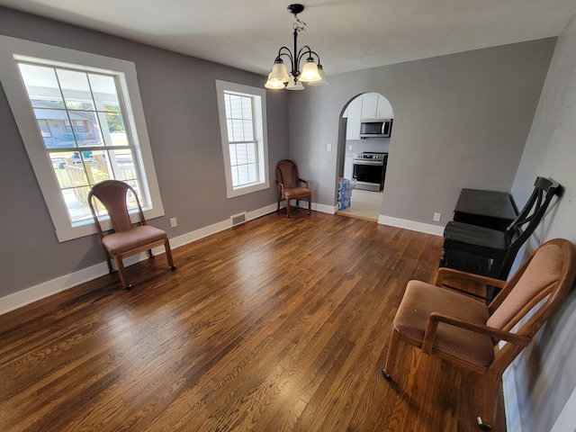 living area featuring a notable chandelier, a healthy amount of sunlight, and dark hardwood / wood-style flooring