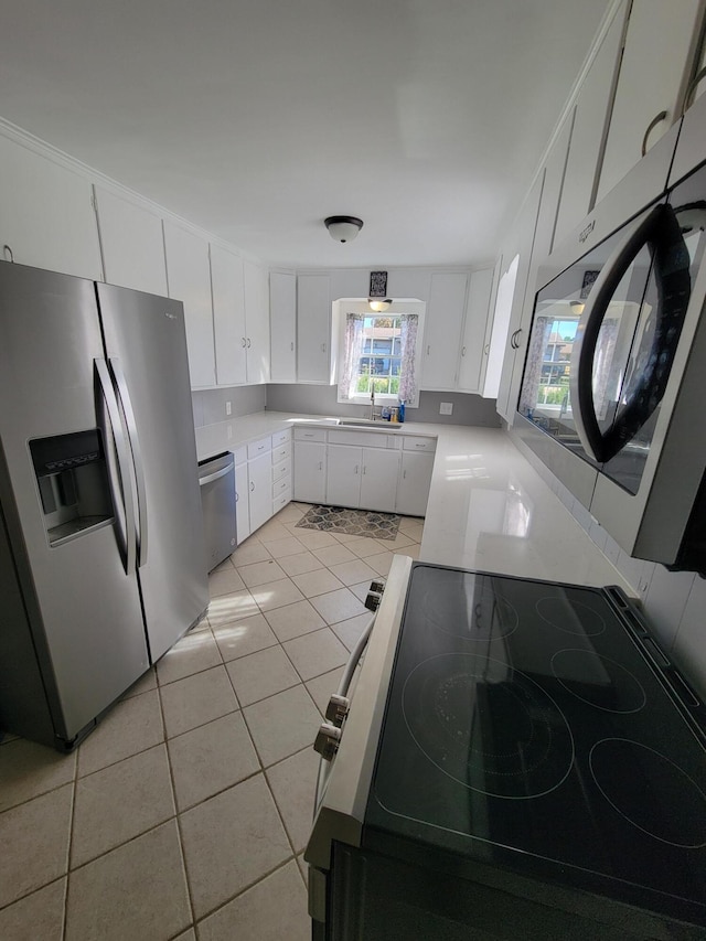 kitchen featuring light tile patterned flooring, sink, washer / dryer, white cabinets, and appliances with stainless steel finishes