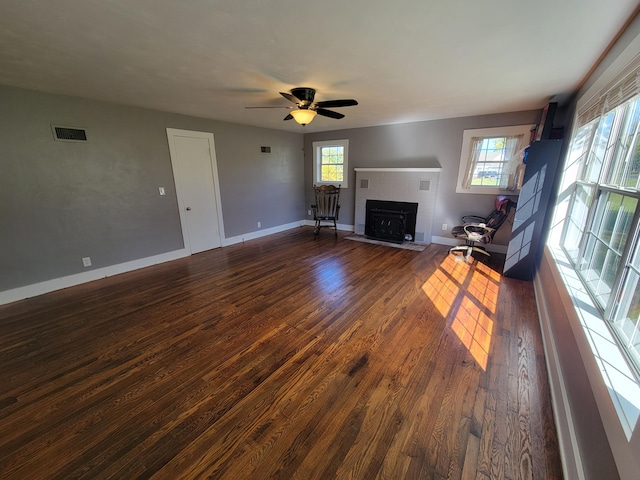 unfurnished living room with ceiling fan, plenty of natural light, and dark wood-type flooring