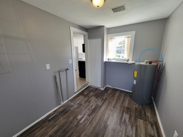 clothes washing area with electric water heater, dark hardwood / wood-style flooring, and wooden walls