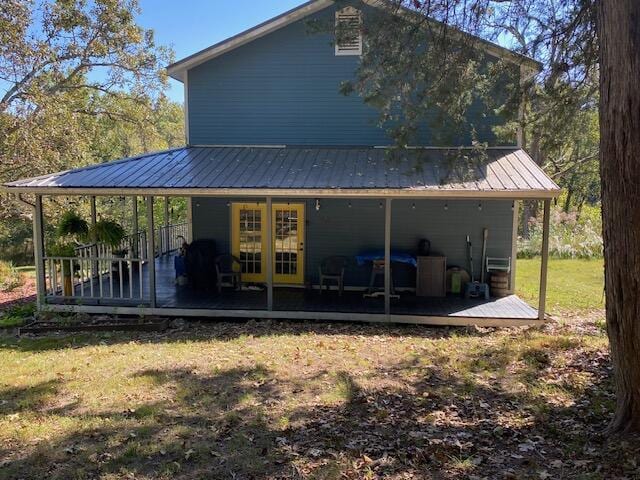 back of house featuring a wooden deck, metal roof, and a lawn