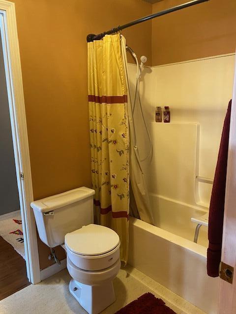 full bathroom with shower / bathtub combination with curtain and toilet