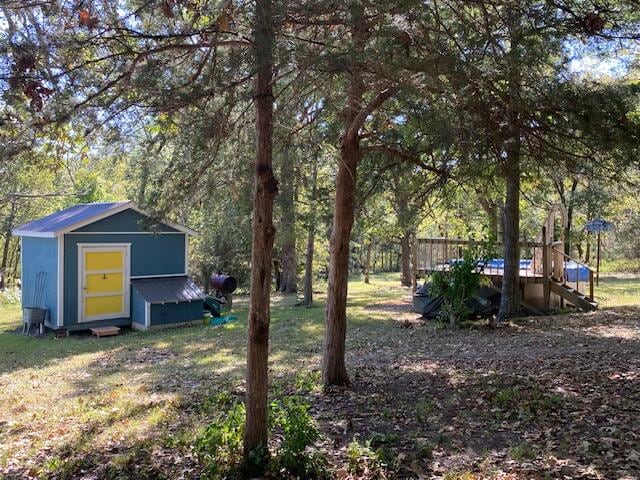 view of yard featuring a wooden deck and a storage unit