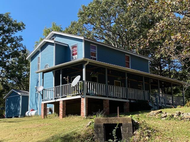 country-style home with an outdoor structure, a front yard, a deck, and a shed