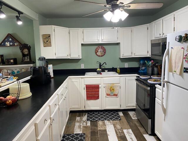 kitchen with black electric range oven, a sink, freestanding refrigerator, and dark countertops