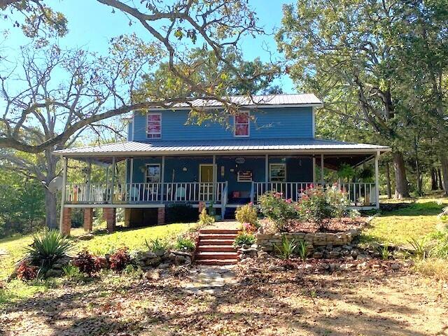 farmhouse inspired home with metal roof, stairs, and covered porch