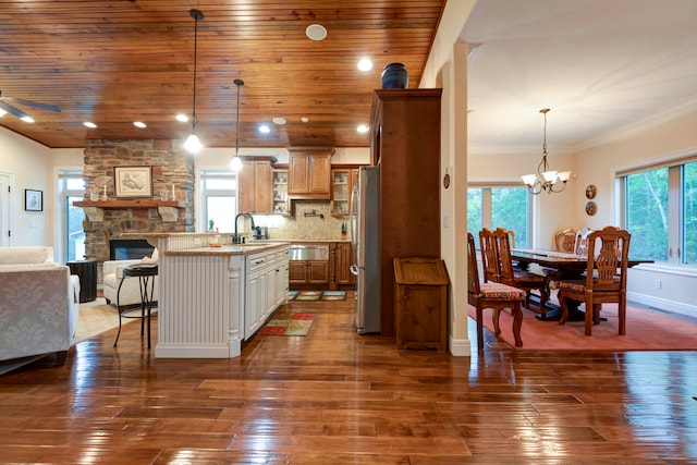 kitchen featuring a breakfast bar, stainless steel fridge, dark wood-type flooring, sink, and decorative light fixtures