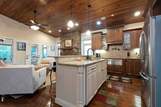 kitchen featuring lofted ceiling, a breakfast bar, stainless steel fridge, sink, and dark hardwood / wood-style flooring