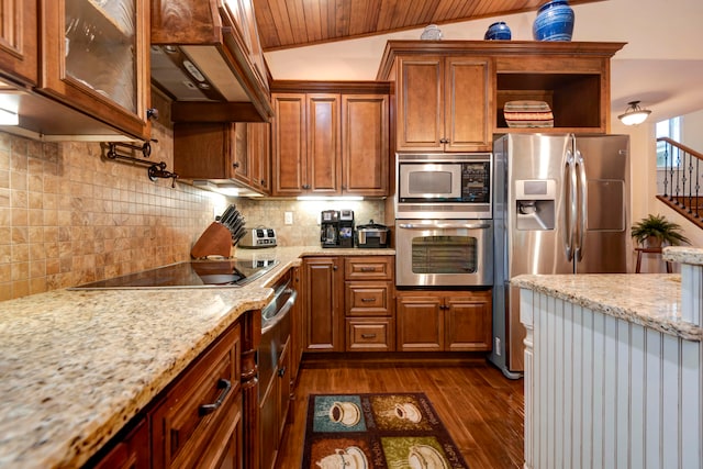 kitchen with lofted ceiling, dark wood-type flooring, appliances with stainless steel finishes, custom range hood, and light stone countertops