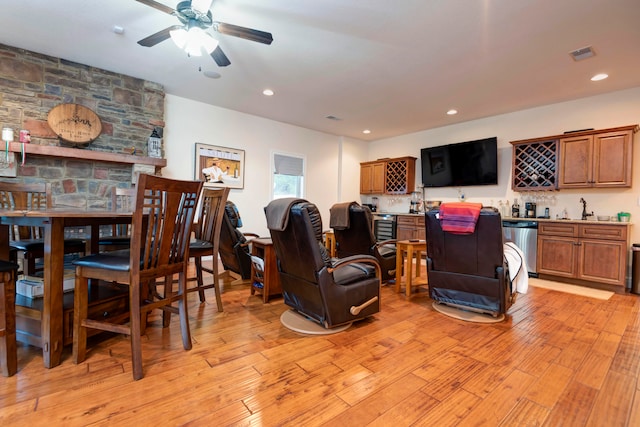 living room with ceiling fan, light hardwood / wood-style floors, and indoor wet bar