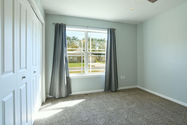 spare room with ceiling fan, plenty of natural light, and carpet flooring