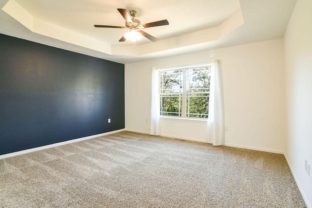 carpeted empty room featuring ceiling fan and a tray ceiling