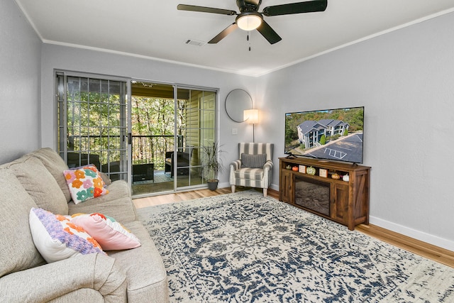 living room featuring wood-type flooring, crown molding, and ceiling fan