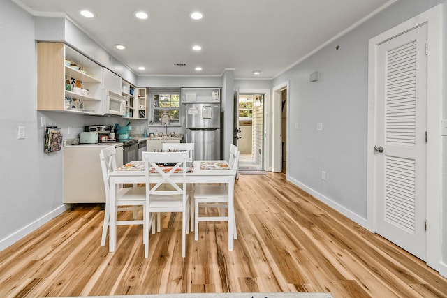 dining room with sink, crown molding, and light hardwood / wood-style floors