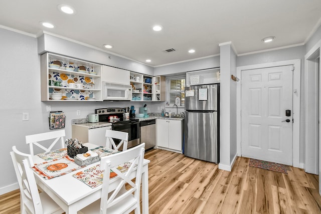 kitchen featuring white cabinets, ornamental molding, sink, light hardwood / wood-style flooring, and appliances with stainless steel finishes