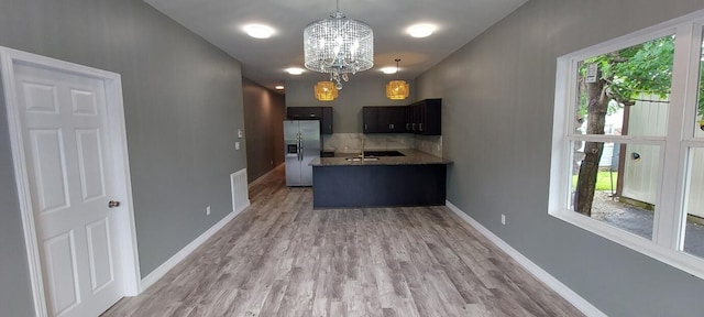 kitchen featuring light wood-type flooring, dark brown cabinetry, stainless steel fridge, an inviting chandelier, and decorative light fixtures