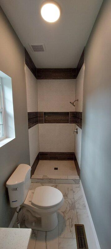 bathroom featuring walk in shower and toilet