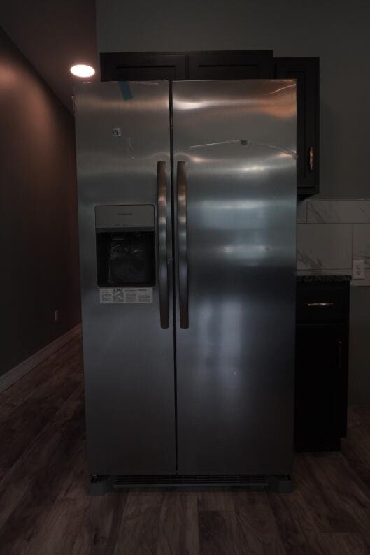 interior details featuring stainless steel refrigerator with ice dispenser, stone counters, dark hardwood / wood-style floors, and tasteful backsplash