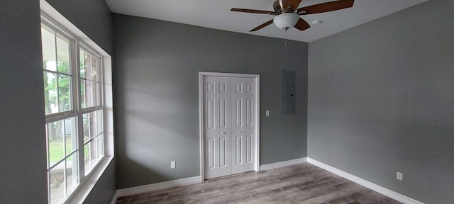 unfurnished room with ceiling fan, electric panel, light hardwood / wood-style floors, and a healthy amount of sunlight