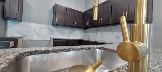 kitchen featuring dark brown cabinetry, decorative backsplash, and stone countertops