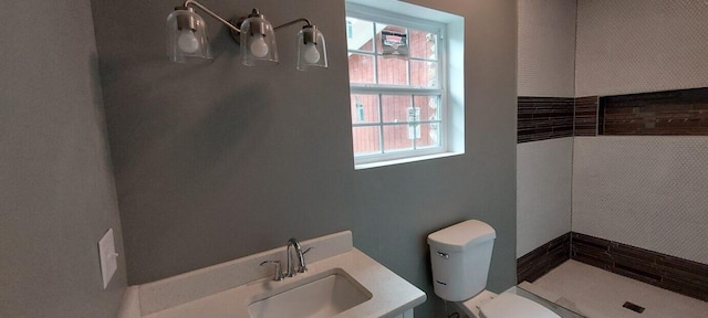 bathroom with a tile shower, sink, toilet, and a wealth of natural light