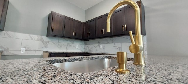 kitchen with tasteful backsplash, light stone countertops, and dark brown cabinetry