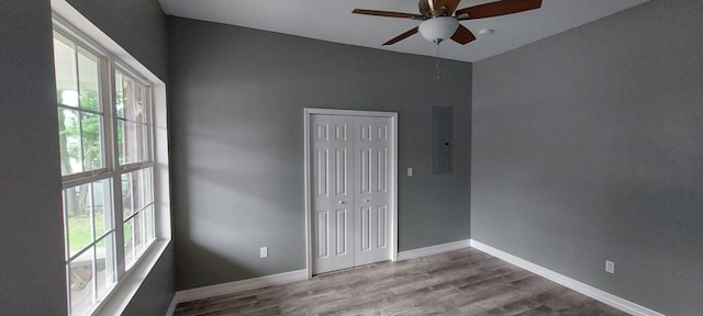 spare room featuring electric panel, ceiling fan, hardwood / wood-style flooring, and a healthy amount of sunlight