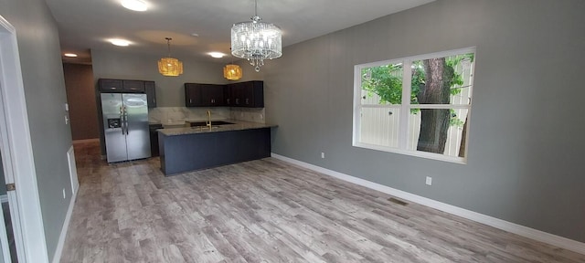 kitchen featuring light wood-type flooring, pendant lighting, dark brown cabinets, sink, and stainless steel fridge with ice dispenser