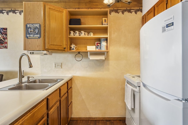 kitchen with white refrigerator, backsplash, dark wood-type flooring, and sink