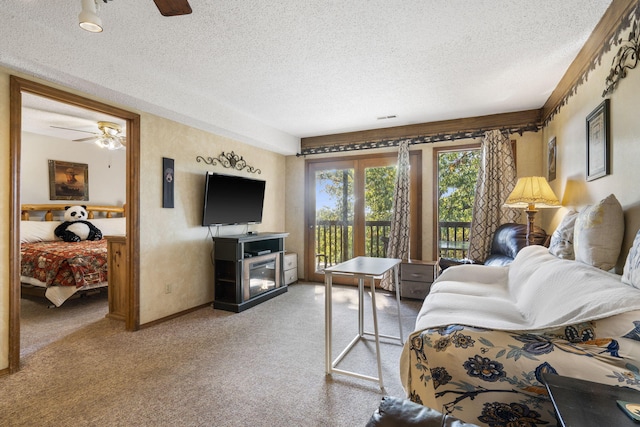 living room featuring ceiling fan, carpet floors, and a textured ceiling