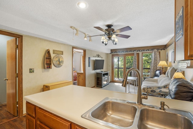 kitchen featuring ceiling fan, sink, a textured ceiling, dark hardwood / wood-style floors, and track lighting