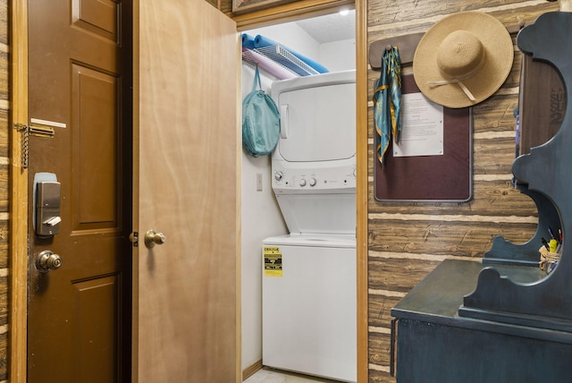 washroom featuring wood walls and stacked washing maching and dryer