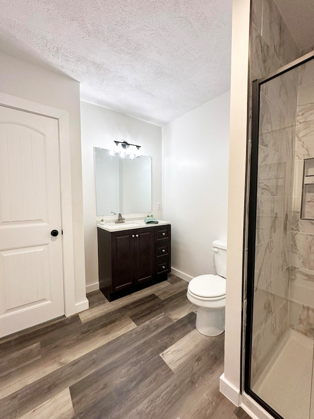 bathroom with vanity, a textured ceiling, an enclosed shower, hardwood / wood-style floors, and toilet