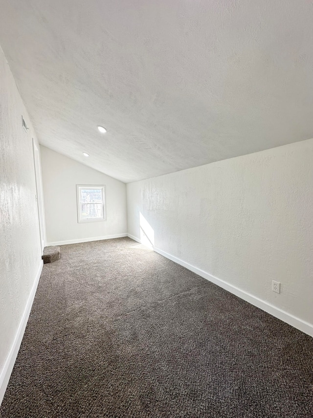 carpeted spare room with a textured ceiling and vaulted ceiling