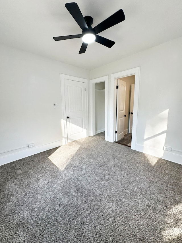 unfurnished bedroom with ceiling fan and dark carpet