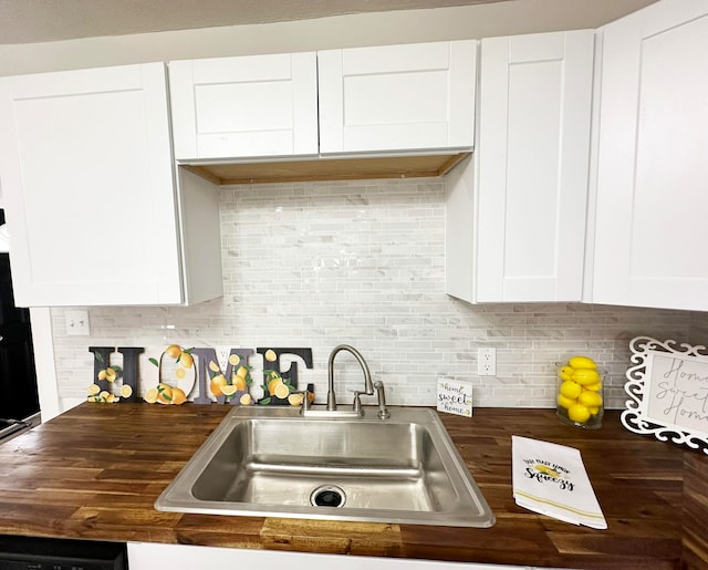 kitchen with butcher block counters, sink, and white cabinets