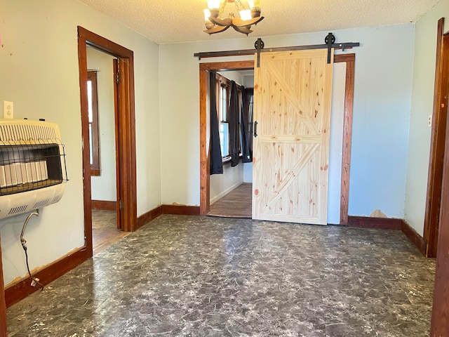 empty room featuring a barn door, heating unit, and a textured ceiling