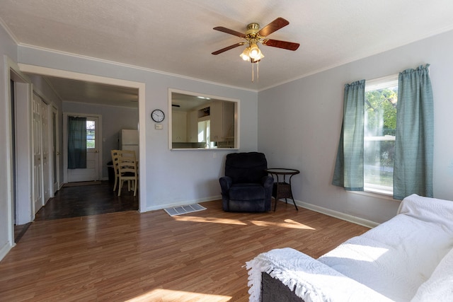 living room featuring a textured ceiling, crown molding, ceiling fan, and dark hardwood / wood-style flooring