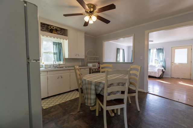 dining area featuring ornamental molding, ceiling fan, sink, and dark hardwood / wood-style flooring