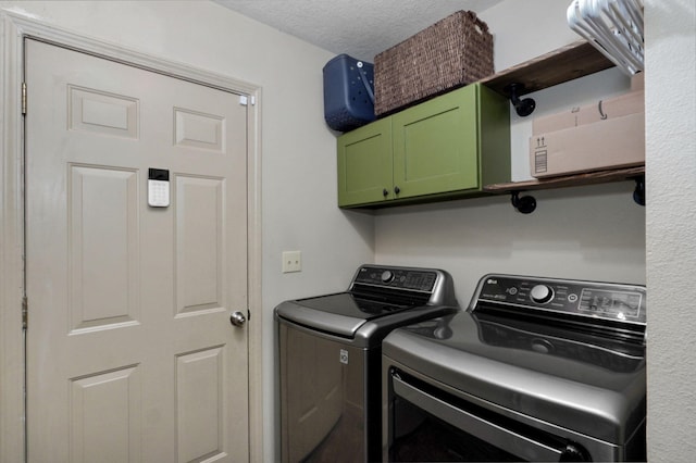 washroom with a textured ceiling, washing machine and clothes dryer, and cabinets