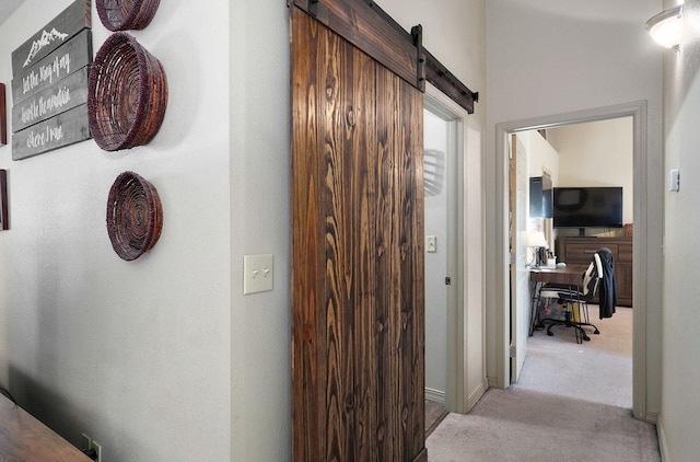 hallway with light carpet and a barn door