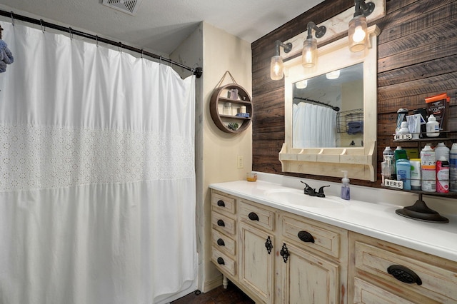 bathroom featuring vanity, wood walls, a textured ceiling, and a shower with shower curtain